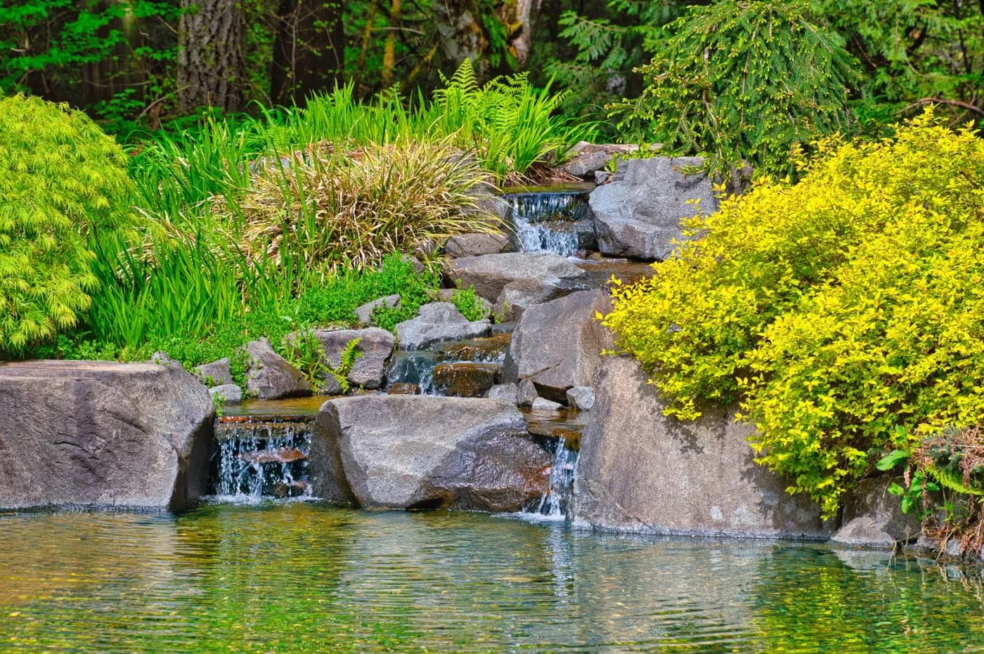 Close-up of water cascading over travertine steps into a lit basin in an Al Ain garden