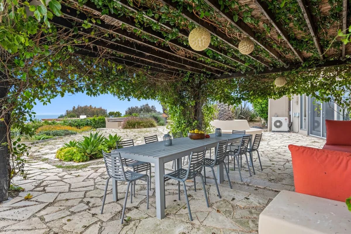 Stone pergola outdoor dining area with built-in seating beside the pool, Dubai Hills villa garden