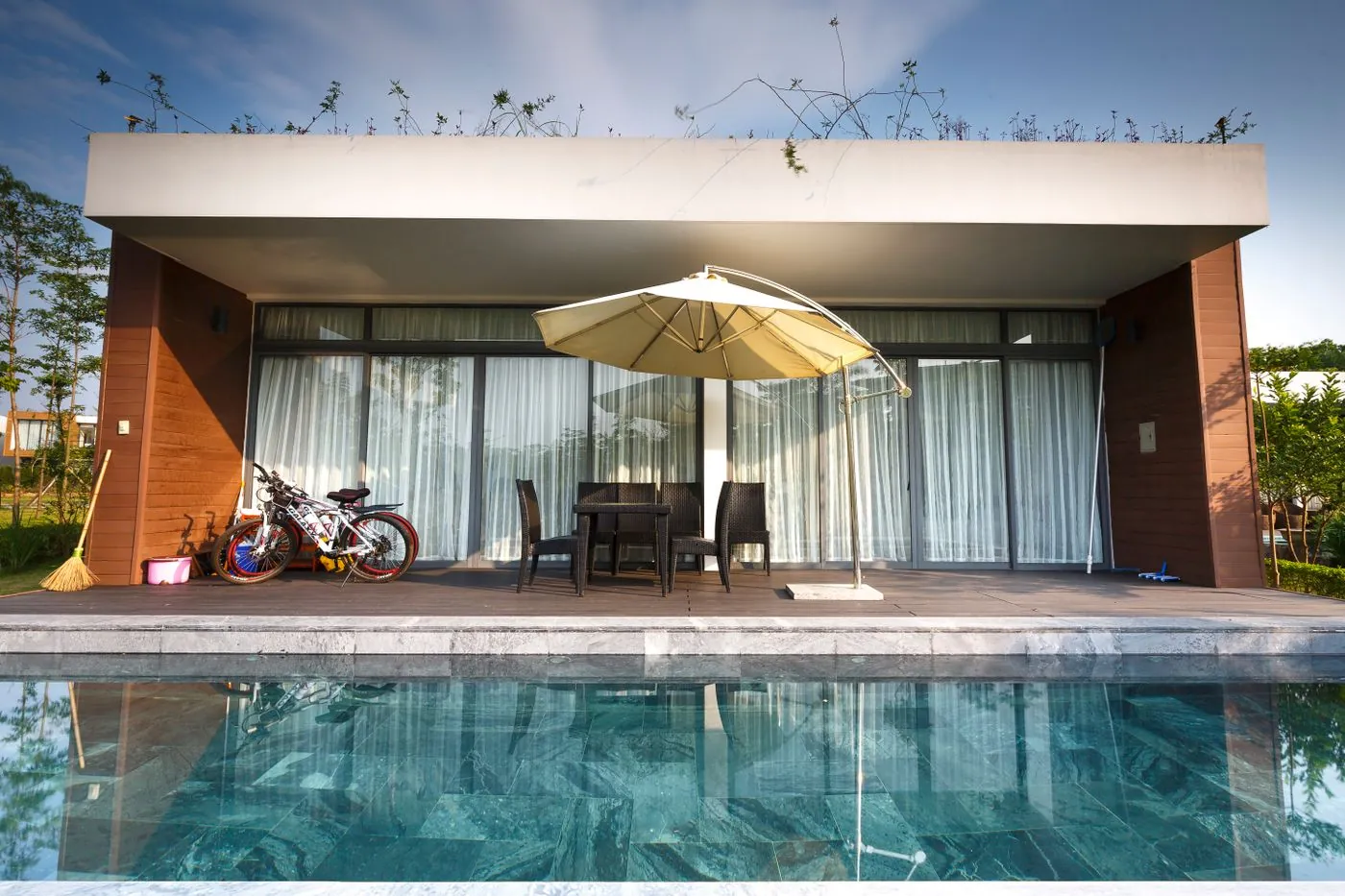 Resort-style villa swimming pool in the UAE with travertine decking, palms and loungers landscaped by Absher Landscaping