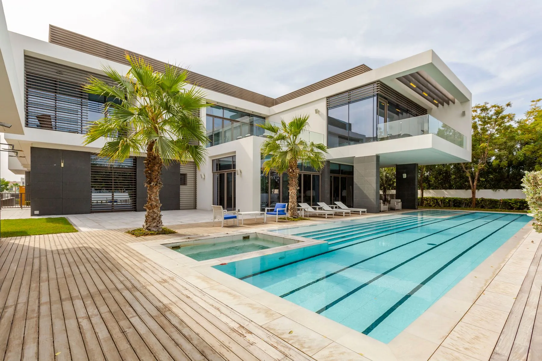 Contemporary villa in Dubai Hills Estate with a resort-style swimming pool framed by date palms and layered planting, landscaped by Absher Landscaping