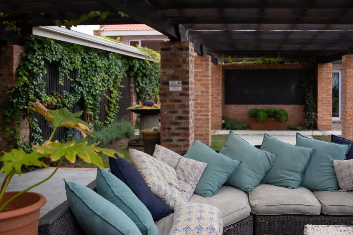Shaded outdoor majlis seating under a timber pergola in an Ajman courtyard garden